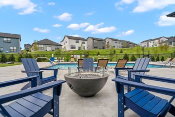 A poolside area with blue chairs and a fire pit.